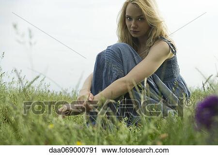 Young woman sitting in field of grass, portrait View Large Photo Image Stock Image - Young woman sitting in field of grass, portrait. Fotosearch