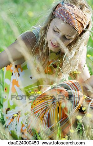 Young woman sitting in field of flowers, looking down, cropped view View Large Photo Image Stock Image - Young woman sitting in field of flowers, looking down, cropped view. Fotosearch