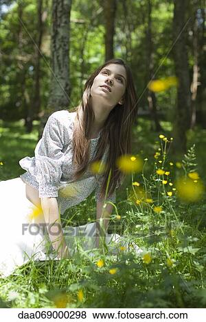 Young woman sitting in forest View Large Photo Image Stock Photo - Young woman sitting in forest. Fotosearch