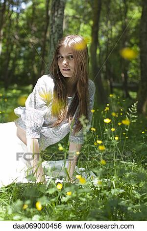 Stock Photograph - Young woman sitting in forest. Fotosearch