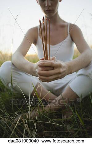 Young woman sitting in grass, holding incense sticks View Large Photo Image Stock Image - Young woman sitting in grass, holding incense sticks. Fotosearch