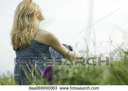 Young woman sitting in grass, daydreaming View Large Photo Image Stock Image - Young woman sitting in grass, daydreaming. Fotosearch