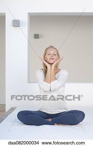 Young woman sitting in indian style with hands under chin, eyes closed View Large Photo Image Picture - Young woman sitting in indian style with hands under chin, eyes closed. Fotosearch