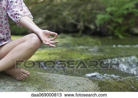 Young woman sitting in lotus position outdoors, cropped View Large Photo Image Stock Image - Young woman sitting in lotus position outdoors, cropped. Fotosearch
