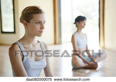 Stock Photography - Young woman sitting in lotus position in yoga class. Fotosearch