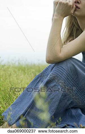 Young woman sitting in meadow, hands under chin, cropped View Large Photo Image Stock Photo - Young woman sitting in meadow, hands under chin, cropped. Fotosearch