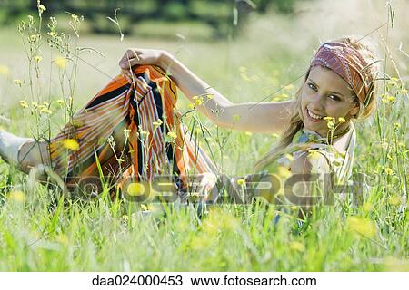 Young woman sitting in tall grass with knees up, smiling at camera View Large Photo Image Stock Image - Young woman sitting in tall grass with knees up, smiling at camera. Fotosearch