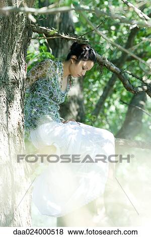 Young woman sitting in tree with eyes closed View Large Photo Image Stock Photo - Young woman sitting in tree with eyes closed. Fotosearch