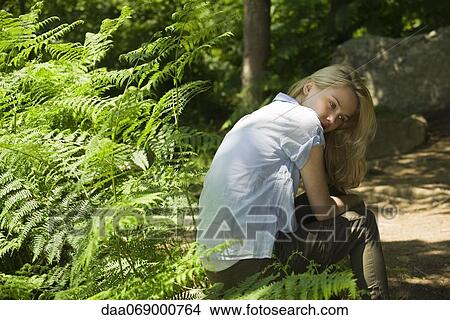 Picture - Young woman sitting in woods. Fotosearch