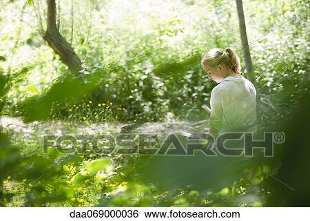 Stock Photograph - Young woman sitting in woods. Fotosearch