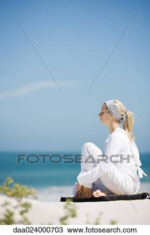 Young woman sitting on beach with knee up, eyes closed View Large Photo Image Stock Image - Young woman sitting on beach with knee up, eyes closed. Fotosearch