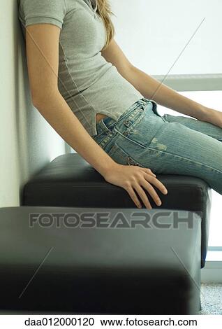 Young woman sitting on bench, mid section View Large Photo Image Stock Image - Young woman sitting on bench, mid section. Fotosearch