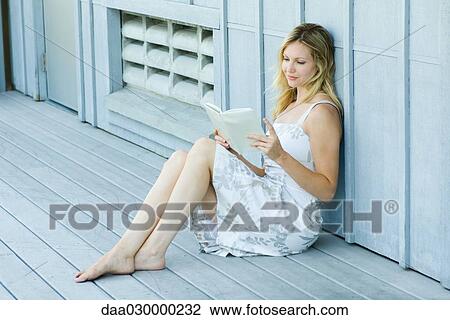 Young woman sitting on deck, reading book View Large Photo Image Stock Image - Young woman sitting on deck, reading book. Fotosearch