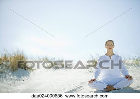 Young woman sitting on dune, full length View Large Photo Image Stock Photograph - Young woman sitting on dune, full length. Fotosearch