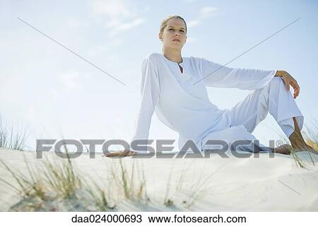 Young woman sitting on dune, low angle view View Large Photo Image Stock Image - Young woman sitting on dune, low angle view. Fotosearch