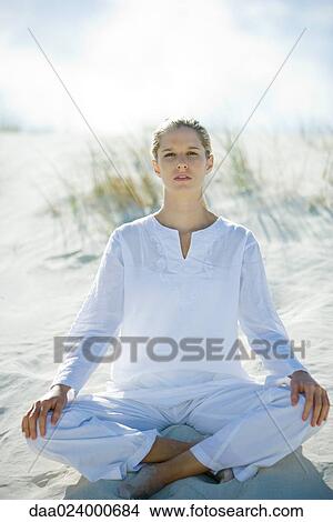 Young woman sitting on dunes, full length View Large Photo Image Picture - Young woman sitting on dunes, full length. Fotosearch