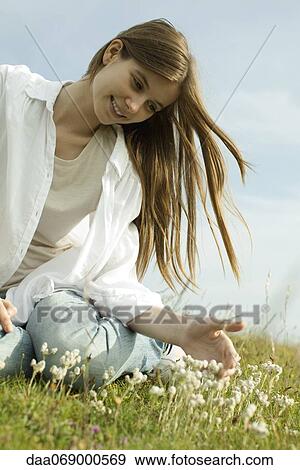 Young woman sitting on meadow with wildflowers View Large Photo Image Stock Photo - Young woman sitting on meadow with wildflowers. Fotosearch