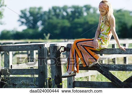 Young woman sitting on top of rural fence, looking down View Large Photo Image Picture - Young woman sitting on top of rural fence, looking down. Fotosearch