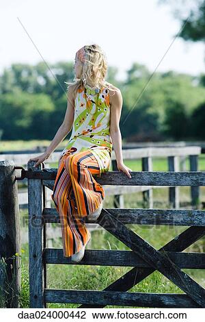 Young woman sitting on top of rural fence, looking away View Large Photo Image Stock Image - Young woman sitting on top of rural fence, looking away. Fotosearch