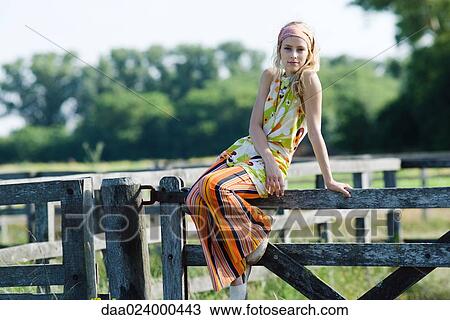 Young woman sitting on top of rural fence, smiling at camera View Large Photo Image Stock Image - Young woman sitting on top of rural fence, smiling at camera. Fotosearch