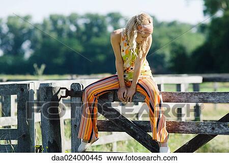Young woman sitting on top of rural fence, looking down View Large Photo Image Stock Photography - Young woman sitting on top of rural fence, looking down. Fotosearch