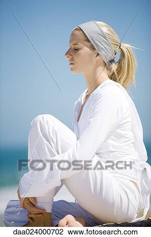 Young woman sitting with knee up, eyes closed View Large Photo Image Stock Image - Young woman sitting with knee up, eyes closed. Fotosearch