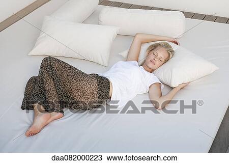 Stock Image - Young woman sleeping on bed. Fotosearch
