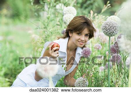 Young woman smelling allium flower, holding sprig of herbs and apple View Large Photo Image Stock Image - Young woman smelling allium flower, holding sprig of herbs and apple. Fotosearch