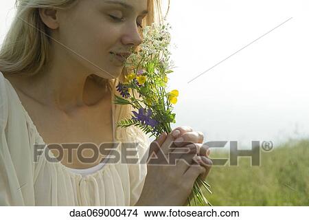 Picture - Young woman smelling bouquet of wildflowers, cropped. Fotosearch