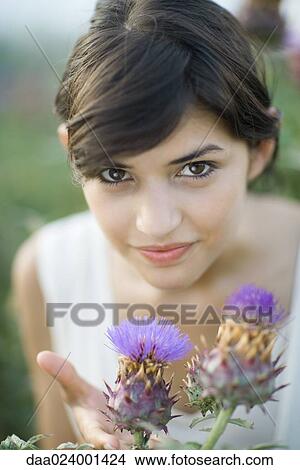 Picture - Young woman smelling thistle flowers. Fotosearch