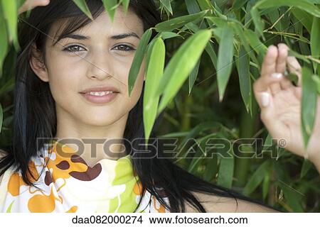 Young woman smiling amongst bamboo foliage, portrait View Large Photo Image Picture - Young woman smiling amongst bamboo foliage, portrait. Fotosearch