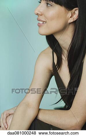 Young woman smiling and looking away in thought, portrait View Large Photo Image Stock Photo - Young woman smiling and looking away in thought, portrait. Fotosearch
