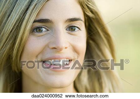Stock Image - Young woman smiling at camera, portrait, close-up. Fotosearch