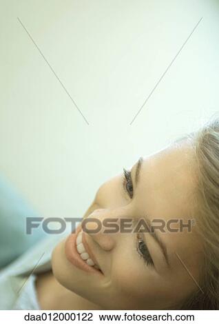 Stock Image - Young woman smiling, close-up of face. Fotosearch