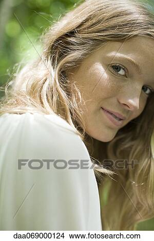 Young woman smiling over shoulder at camera, portrait View Large Photo Image Picture - Young woman smiling over shoulder at camera, portrait. Fotosearch