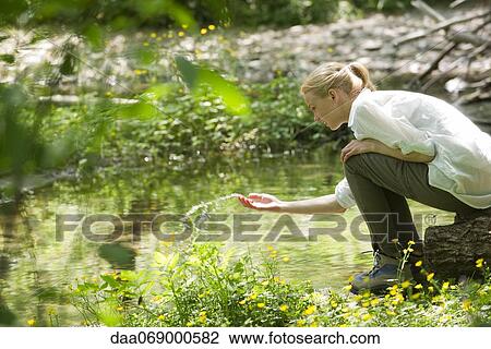 Young woman splashing water by river View Large Photo Image Stock Image - Young woman splashing water by river. Fotosearch