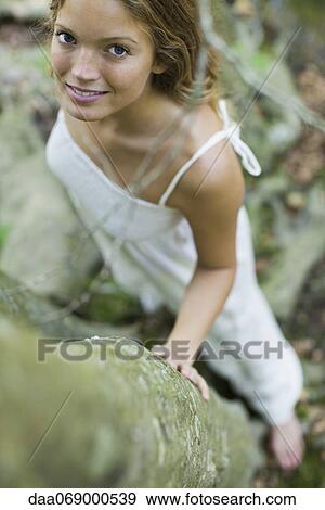 Stock Photo - Young woman standing by trees, high angle view. Fotosearch