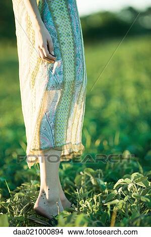 Picture - Young woman standing in field, low section. Fotosearch