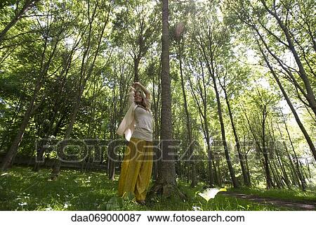 Young woman standing in forest with arms raised in air View Large Photo Image Stock Photo - Young woman standing in forest with arms raised in air. Fotosearch