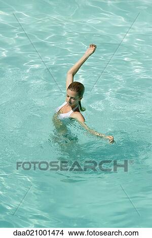 Young woman standing in pool, stretching arms, full length, high angle view View Large Photo Image Picture - Young woman standing in pool, stretching arms, full length, high angle view. Fotosearch