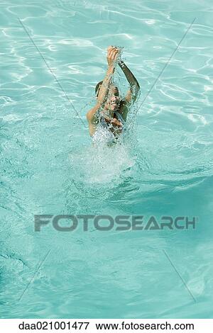 Young woman standing in pool, splashing with arms over head, full length, high angle view View Large Photo Image Stock Photo - Young woman standing in pool, splashing with arms over head, full length, high angle view. Fotosearch
