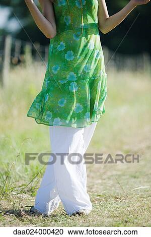 Young woman standing in rural field with legs crossed at knees, cropped view View Large Photo Image Stock Image - Young woman standing in rural field with legs crossed at knees, cropped view. Fotosearch