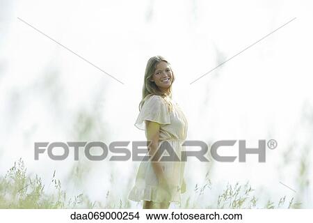Young woman standing in tall grass, portrait View Large Photo Image Picture - Young woman standing in tall grass, portrait. Fotosearch