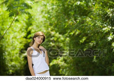 Young woman standing in woods with hand in hair, looking away View Large Photo Image Stock Photography - Young woman standing in woods with hand in hair, looking away. Fotosearch
