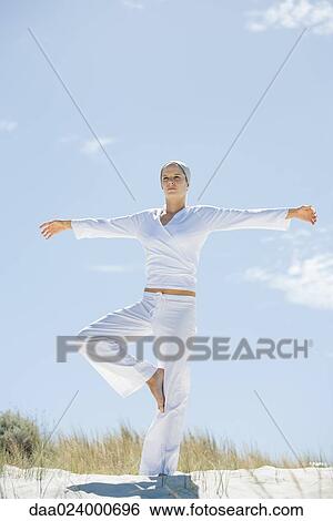 Young woman standing in yoga pose on beach View Large Photo Image Stock Photograph - Young woman standing in yoga pose on beach. Fotosearch