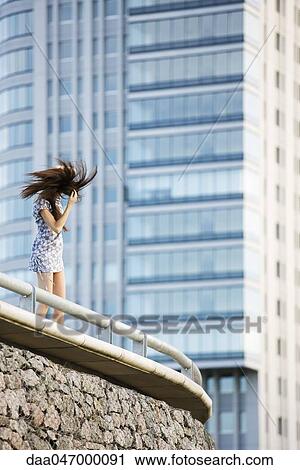 Young woman standing on balcony, tossing hair View Large Photo Image Stock Image - Young woman standing on balcony, tossing hair. Fotosearch