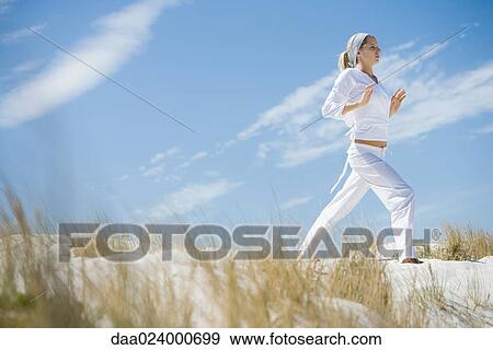 Young woman standing on dune, exercising View Large Photo Image Stock Photo - Young woman standing on dune, exercising. Fotosearch