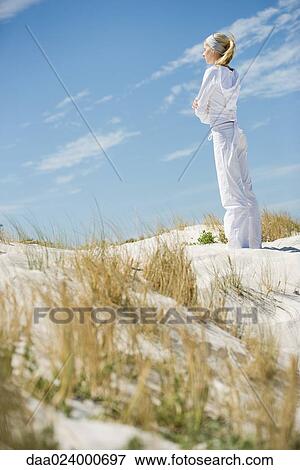 Young woman standing on dune with eyes closed and arms crossed, side view, full length View Large Photo Image Stock Photo - Young woman standing on dune with eyes closed and arms crossed, side view, full length. Fotosearch