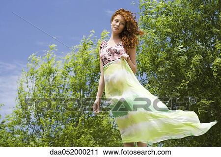 Young woman standing outdoors, holding scarf in wind View Large Photo Image Stock Image - Young woman standing outdoors, holding scarf in wind. Fotosearch