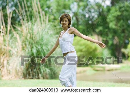 Young woman standing outdoors with arms out, smiling at camera View Large Photo Image Stock Image - Young woman standing outdoors with arms out, smiling at camera. Fotosearch